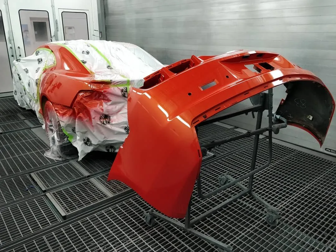 Freshly painted orange bumper in the paint booth